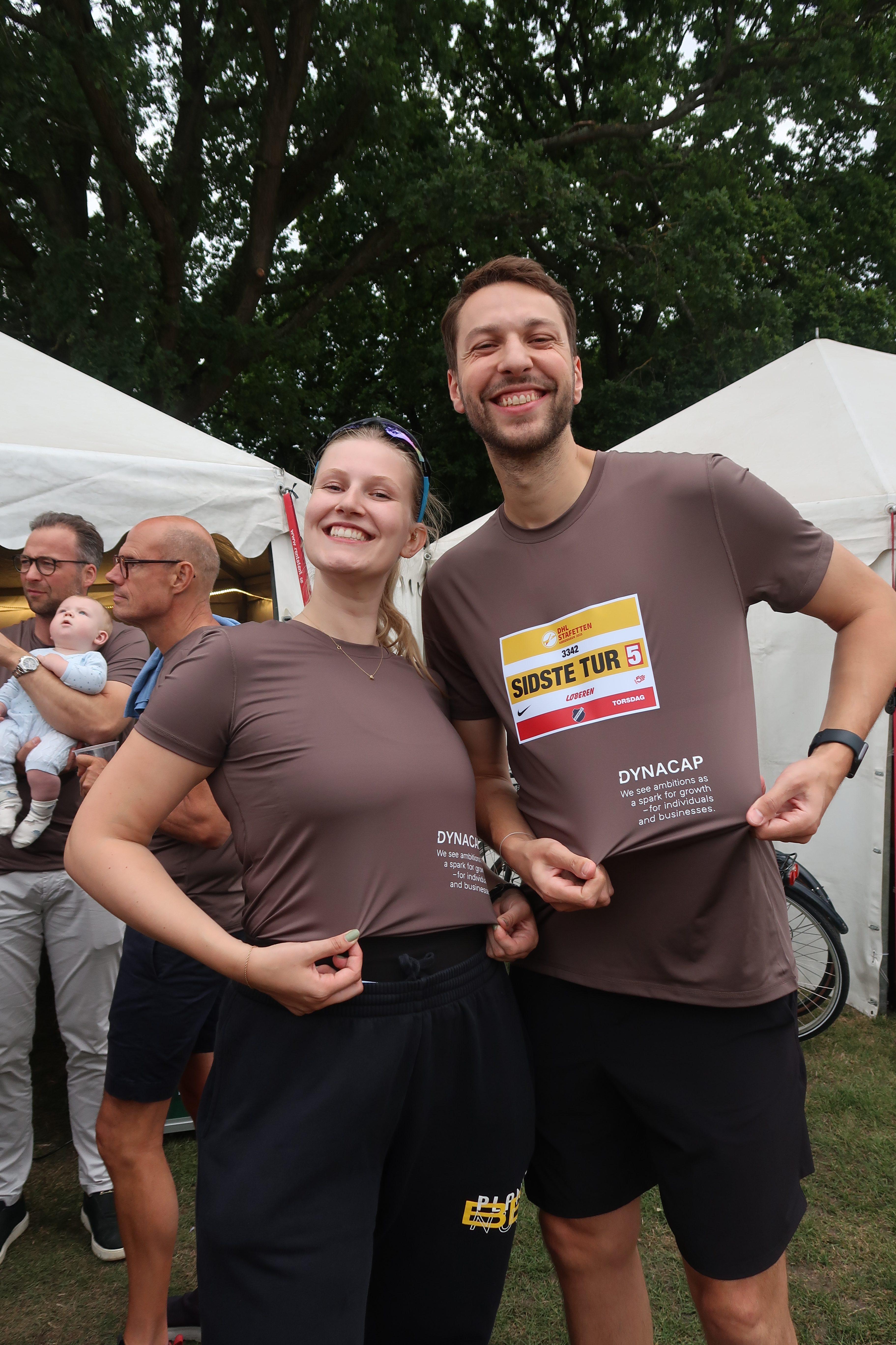 Two people showing off their tshirts at a company run event DHL.
