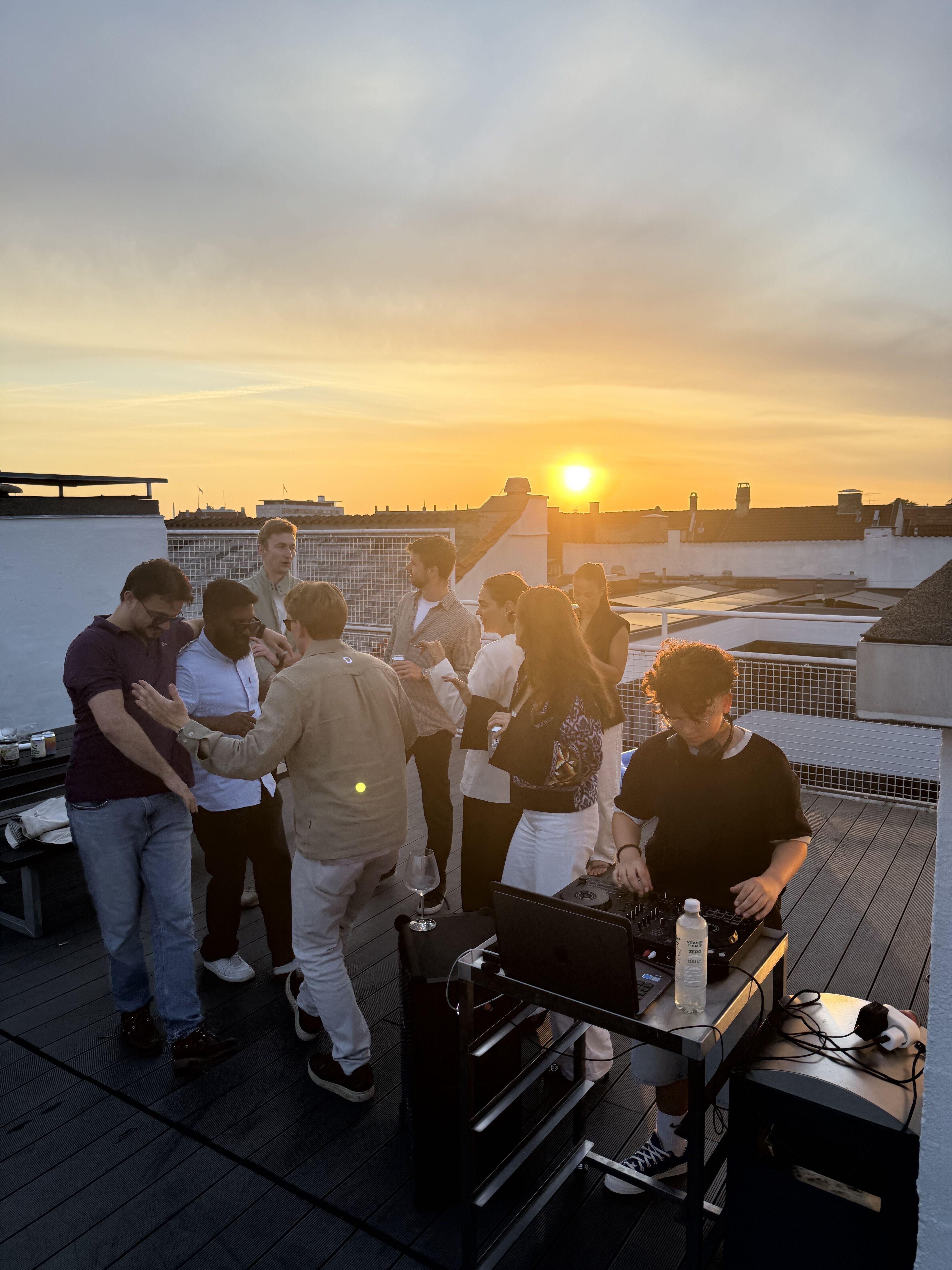 People dancing at a rooftop terrace in the sunset.